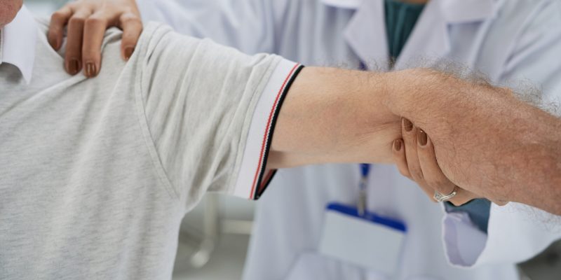 Senior man having shoulder and arm treatment in medical office
