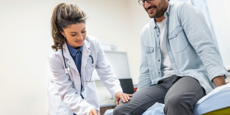 The neurologist testing knee reflex on a male patient using a hammer. Neurological physical examination. Selective focus, close up